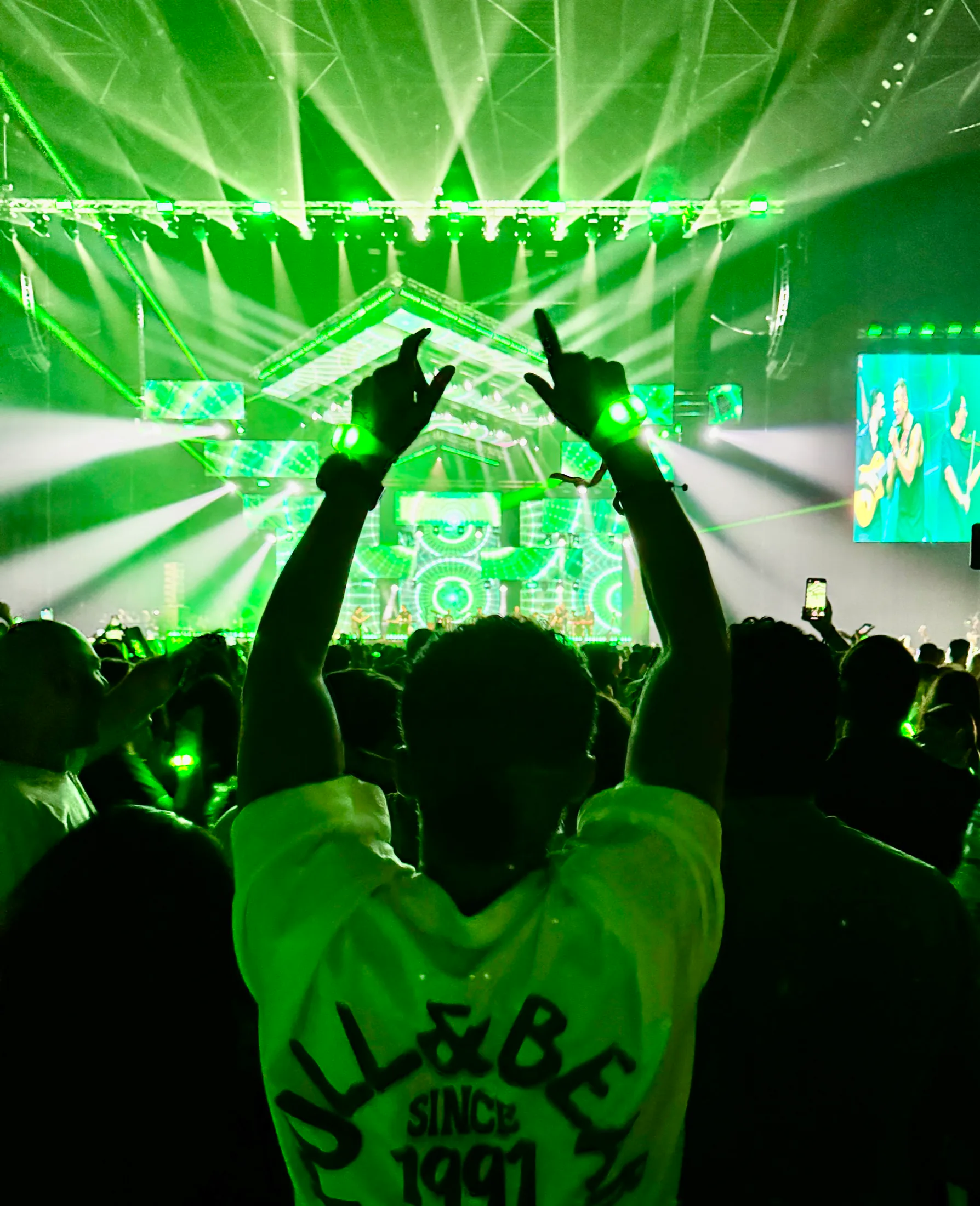 Large-scale live event audience beneath green concert lasers